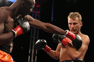 A professional boxer punches his opponent via jabbing. Note the two boxers being bare-chested and without headgear.